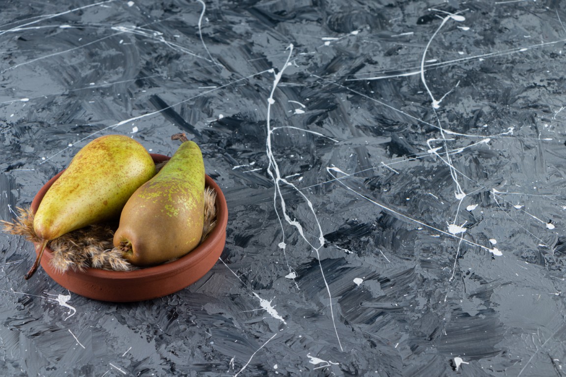 Clay bowl with fresh ripe pears on marble background. High quality photo